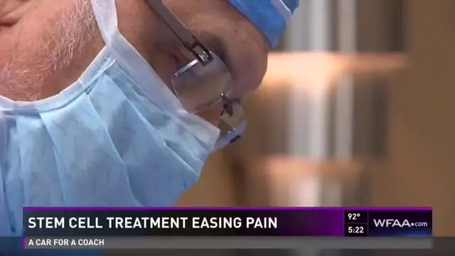 A close-up of a masked medical professional, likely involved in regenerative therapy. News text on screen reads STEM CELL TREATMENT EASING PAIN with a WFAA logo and time and temperature display.